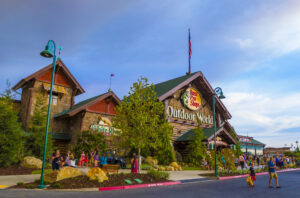 Exterior of Bass Pro Shops entrance with customers entering and exiting