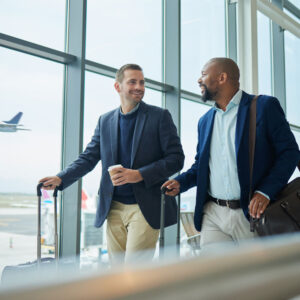 Two professionally dressed men walking in a airport with luggage