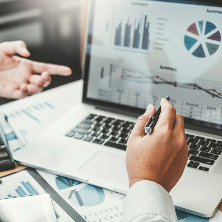 Hands in front of a laptop with the screen showing several charts