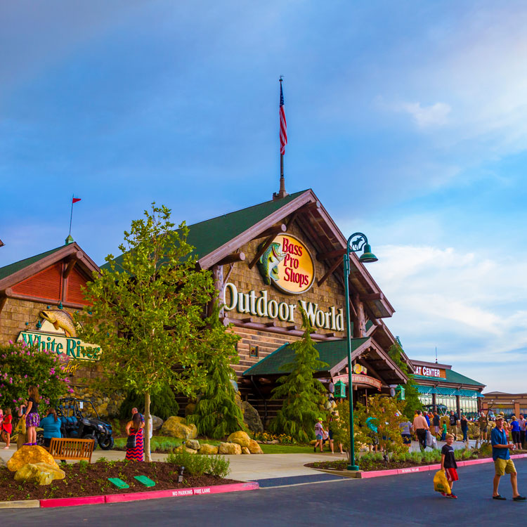 Exterior of Bass Pro Shops entrance with customers entering and exiting