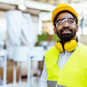 Man in hi-vis vest with safety googles, hard hat, and ear protection
