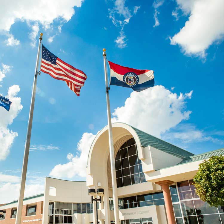 Missouri state flag and US flag flying in front of the entrance to a building at Ozarks Tech