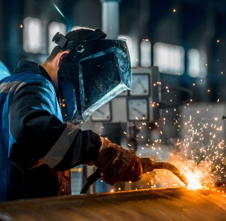Welder in a factory environment working with a blowtorch