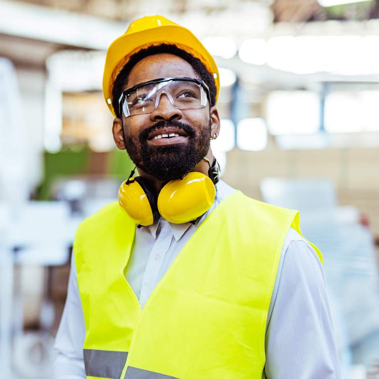 Man in hi-vis vest with safety googles, hard hat, and ear protection