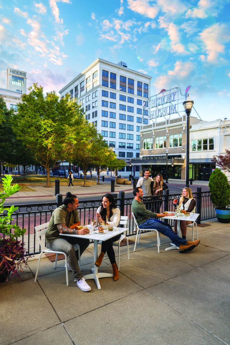 6 people on patio at restaurant in Downtown Springfield Missouri with tall Heers building in background and Springfield's History Museum